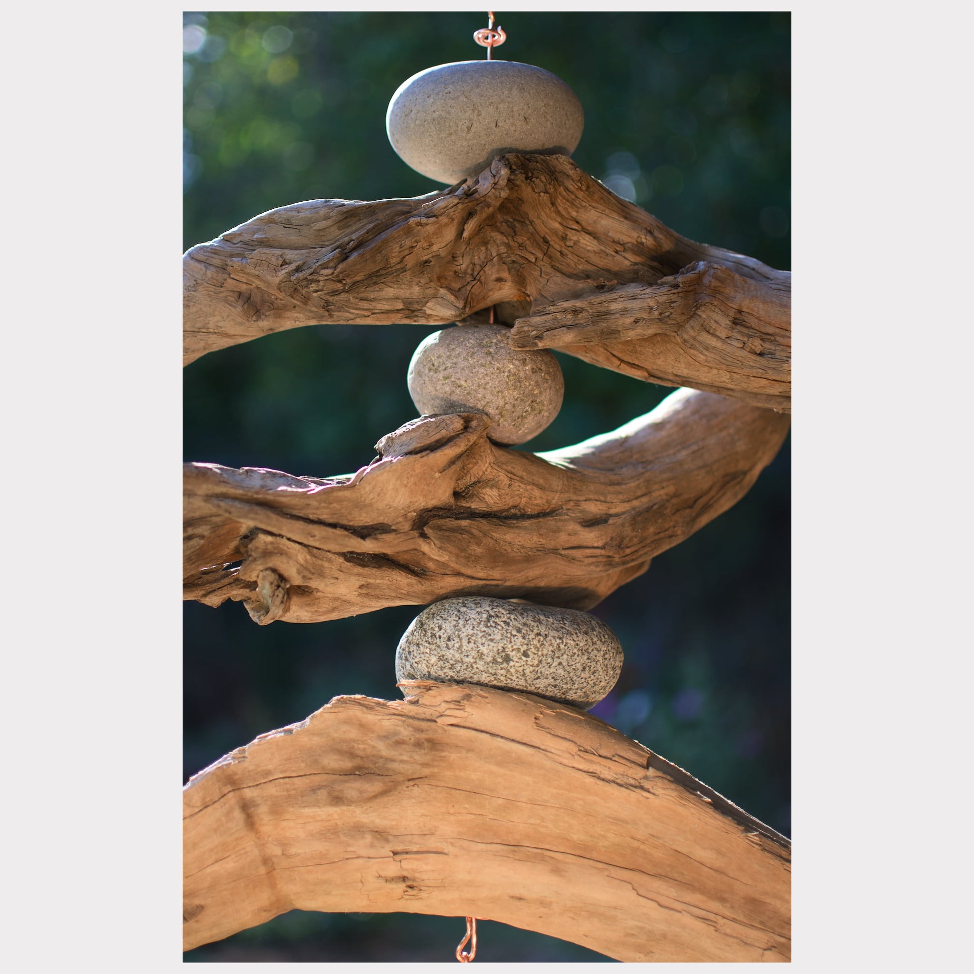 Stack of stones balanced on a piece of driftwood with a blurred natural background