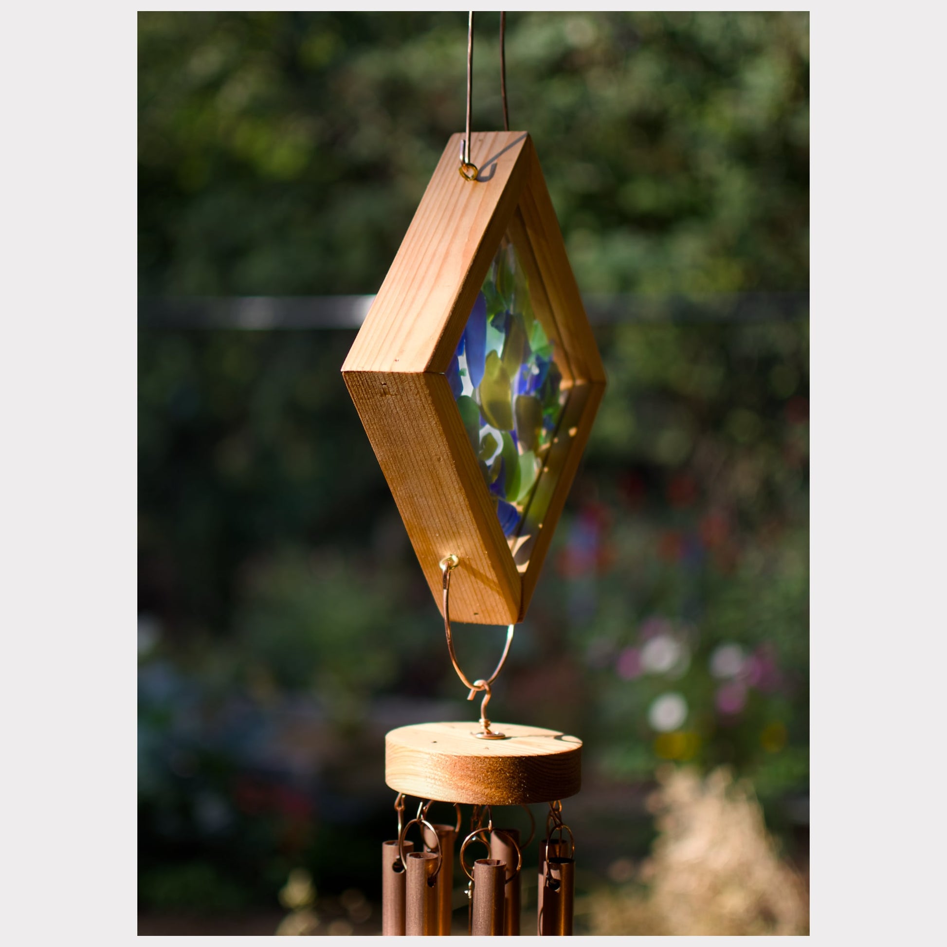 Wooden wind chime with geometric design against a blurred natural background