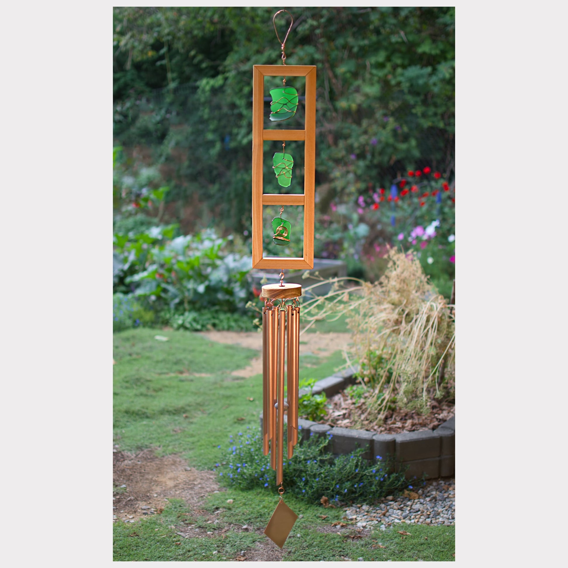 Decorative wind chime with green glass panels in a garden setting