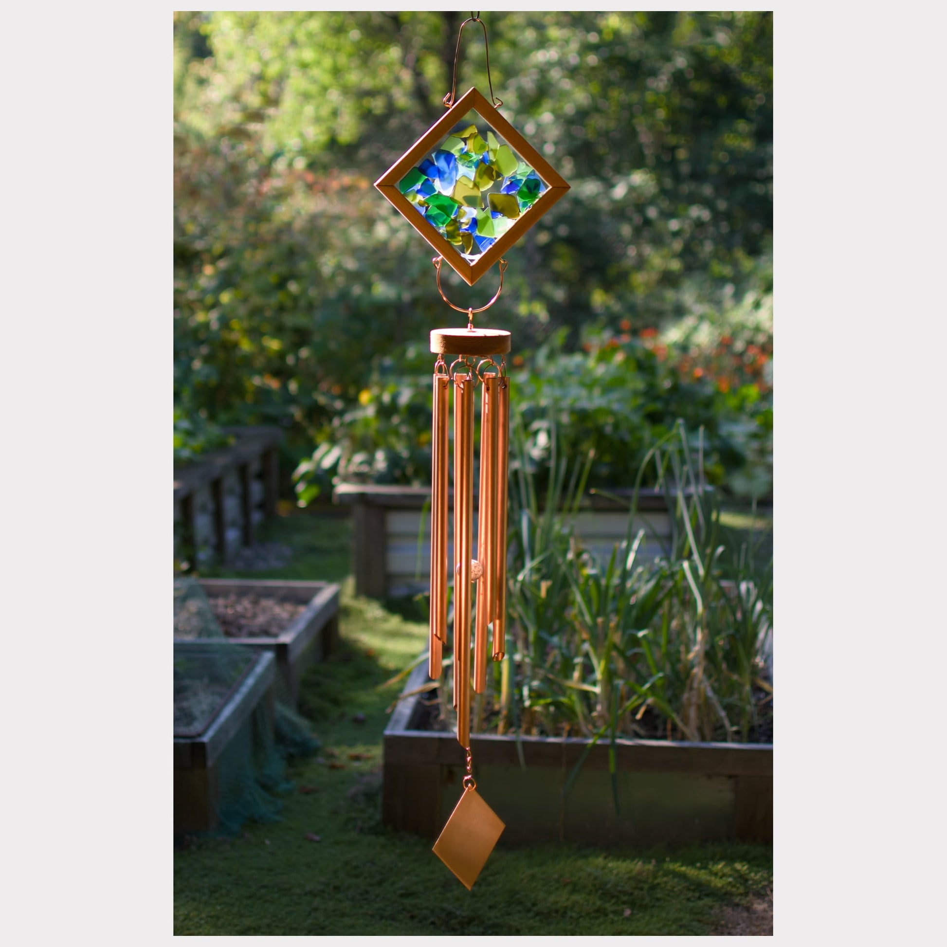 Decorative wind chime with colorful glass panel in a garden setting