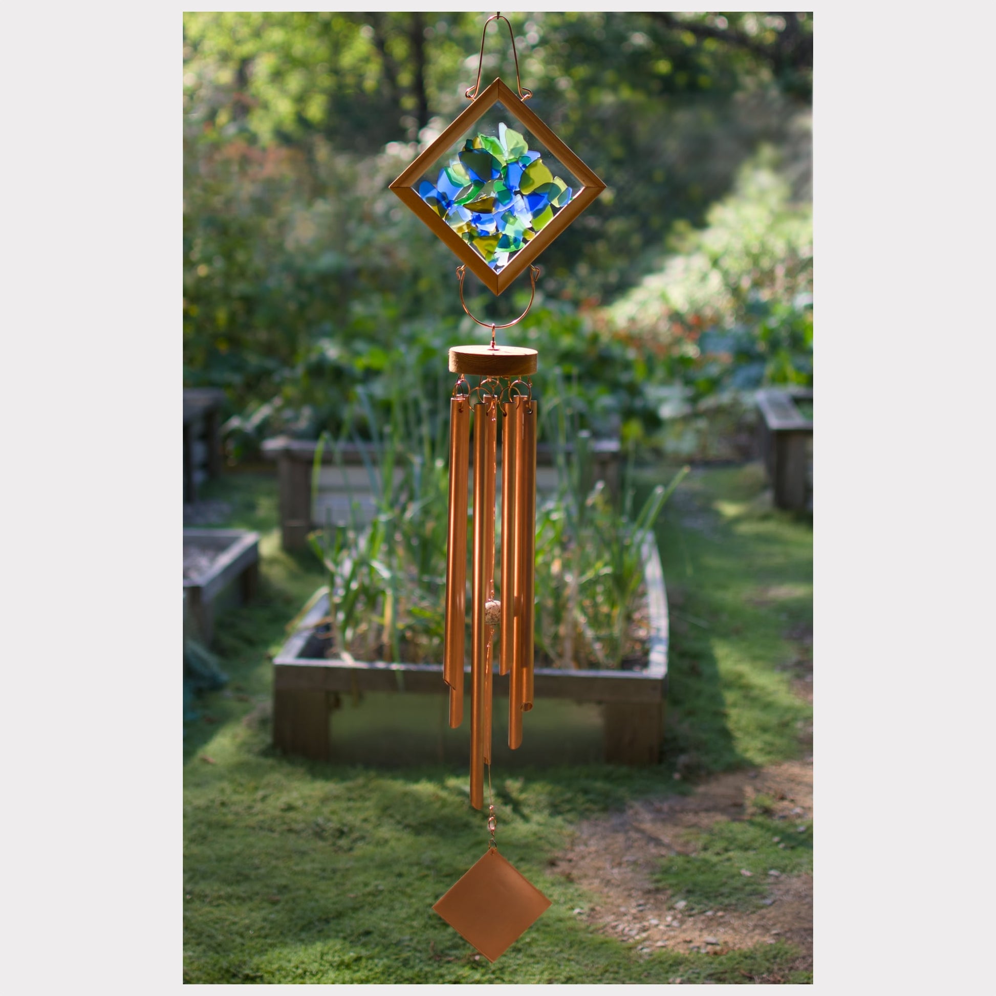 Decorative wind chime with colorful glass panel in a garden setting