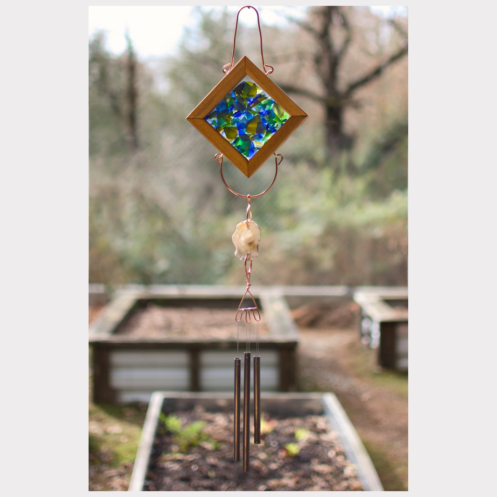 Kaleidoscope wind chime featuring artist-made beach glass, an oyster half shell, and three antiqued brass chimes.