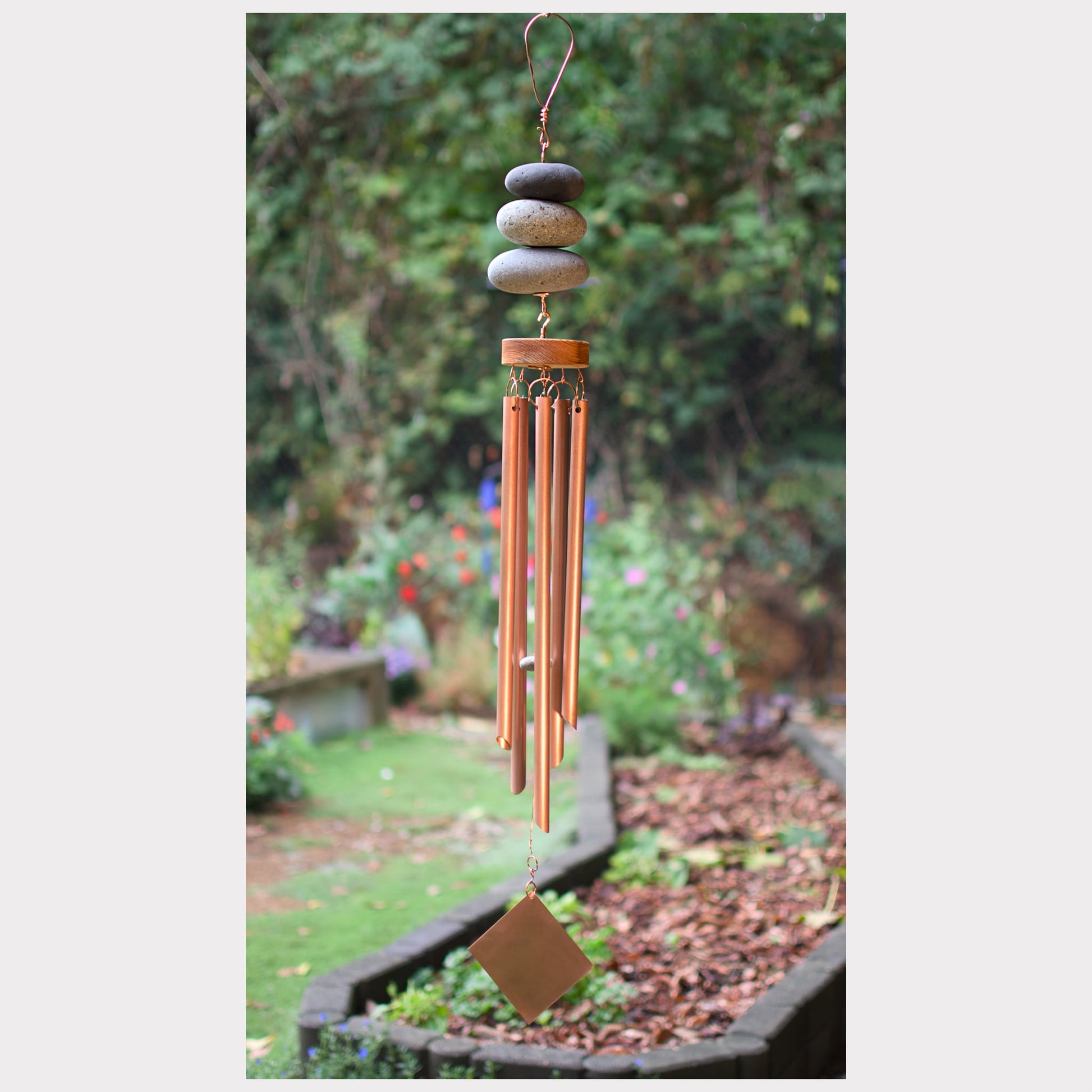 Decorative wind chime with stones on a garden background
