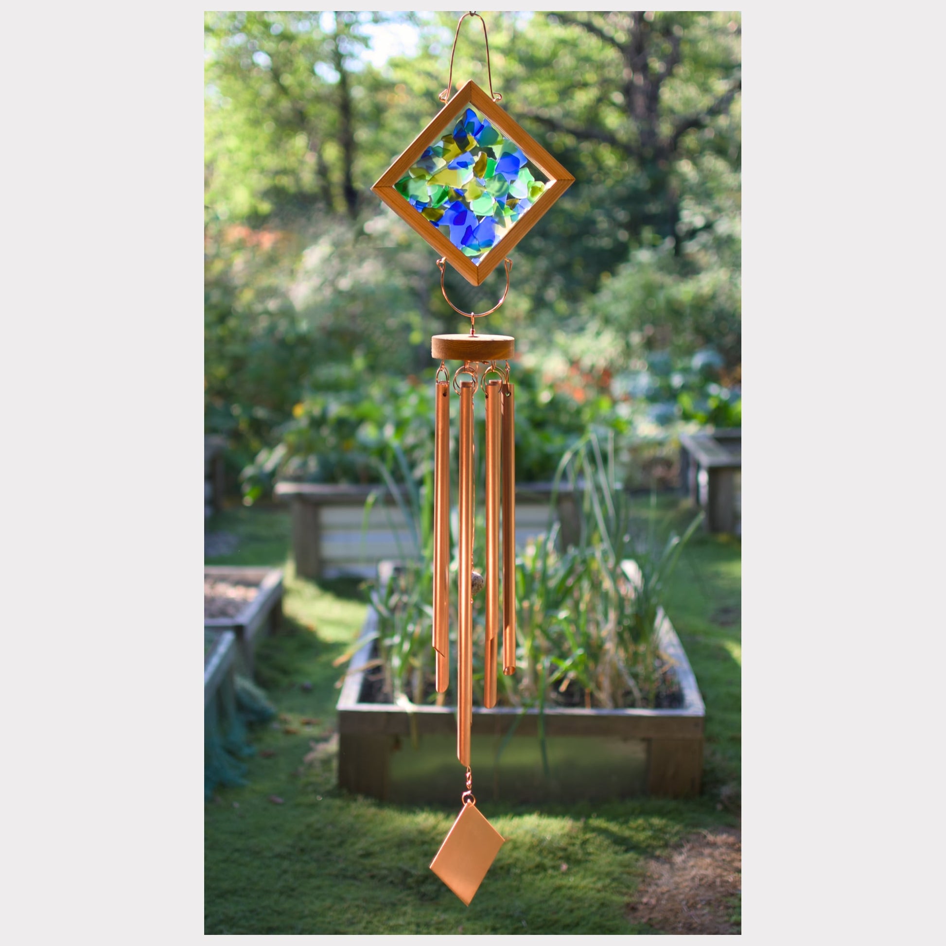 Decorative wind chime with stained glass panel in a garden setting