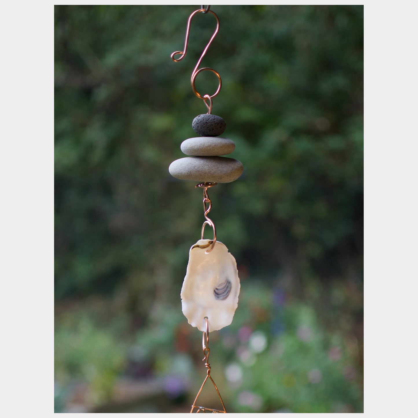 Decorative hanging with stones and a shell against a blurred natural background