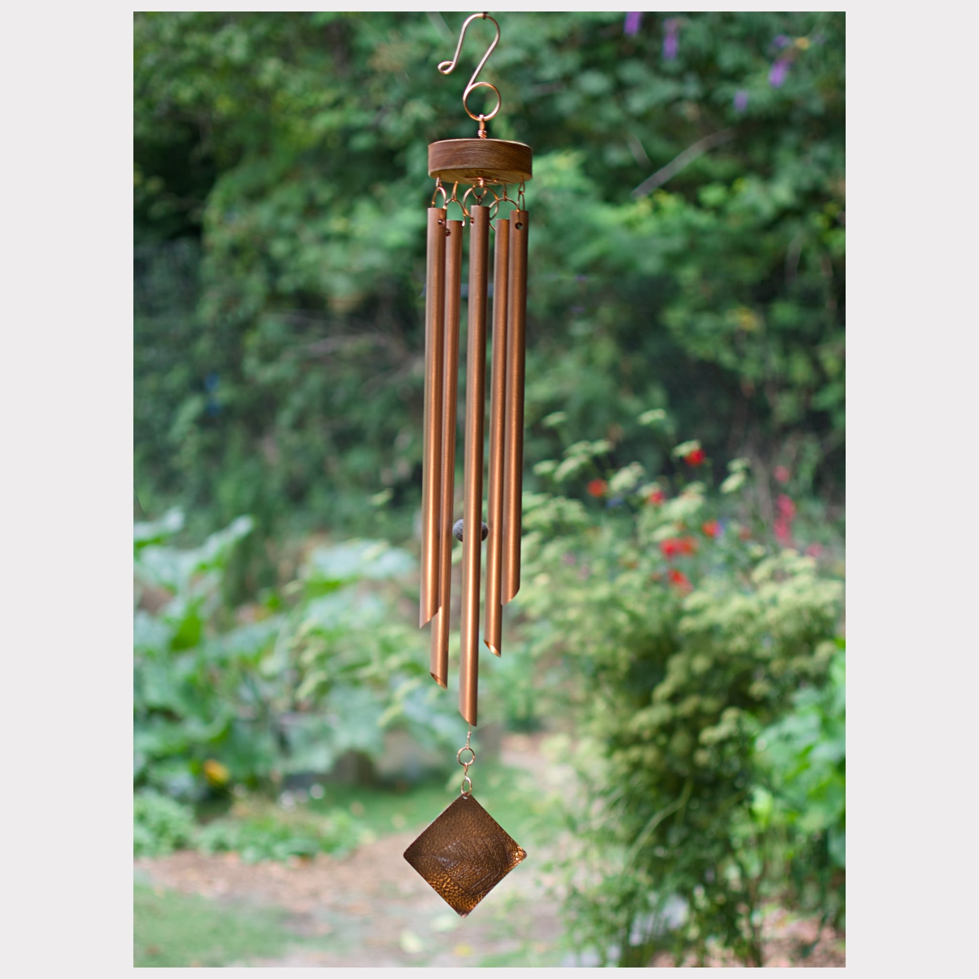 Copper wind chime with a diamond-shaped pendant against a garden background