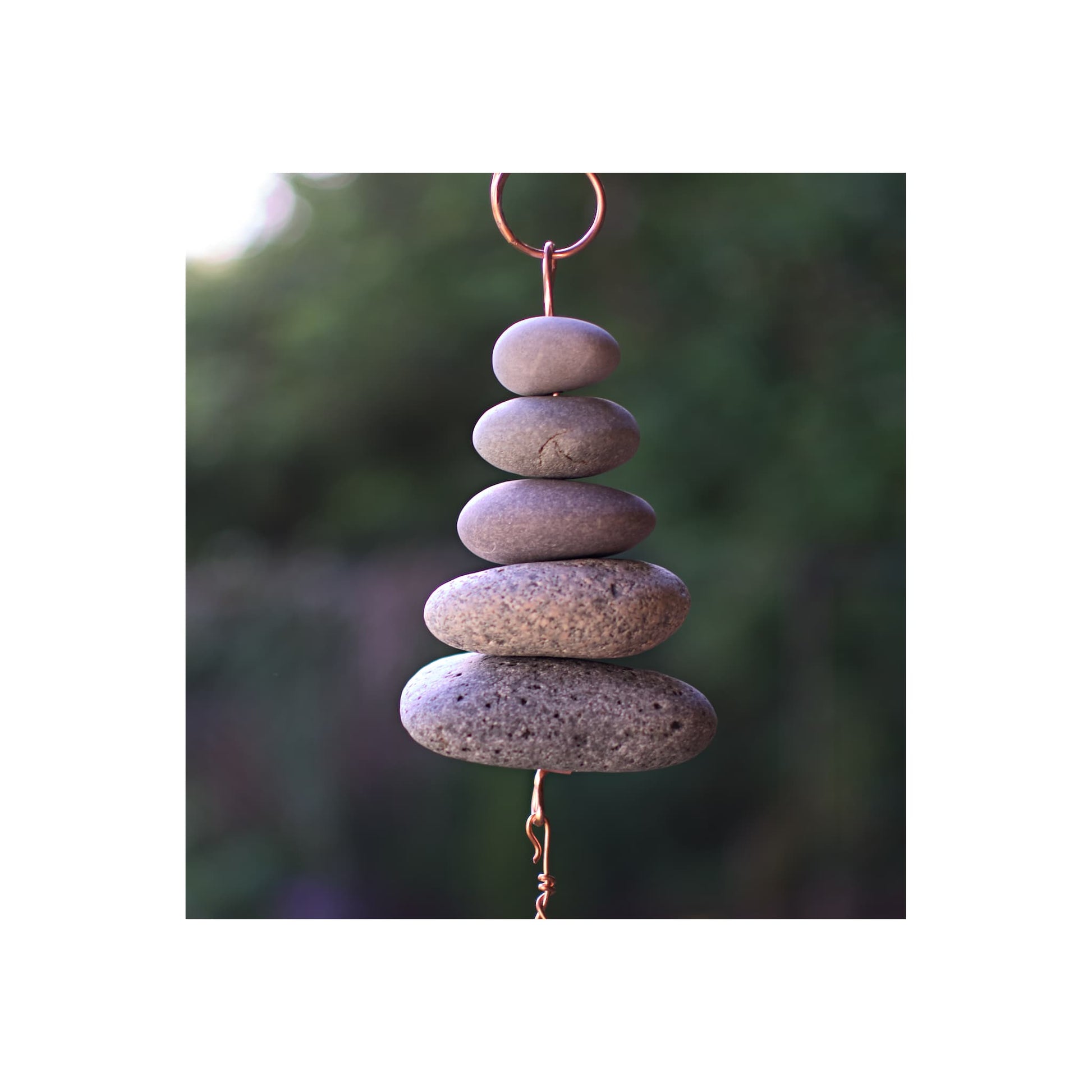 Stack of stones (detail photo from a zen chime) against a blurred natural background