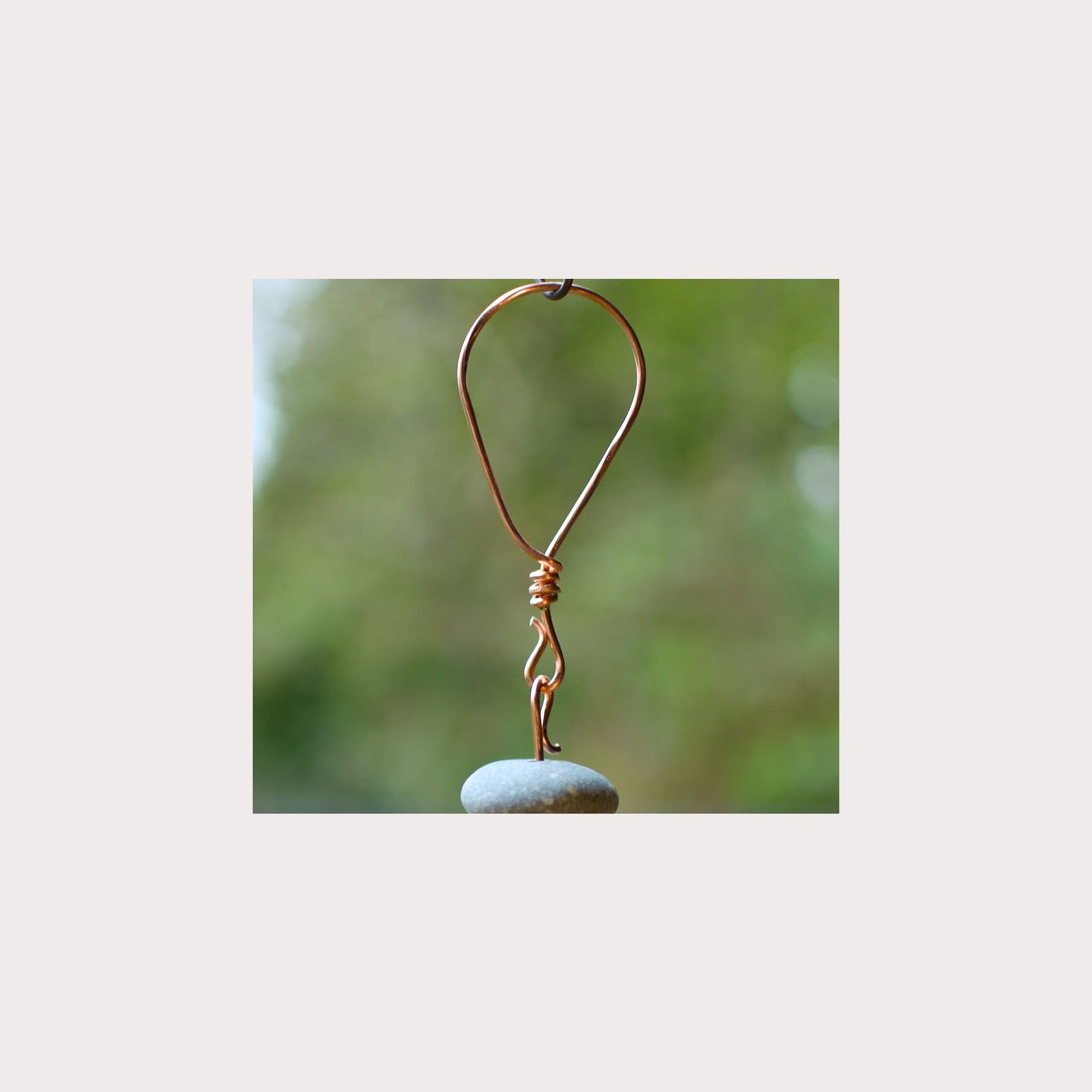 Copper hook with a stone on a blurred green background