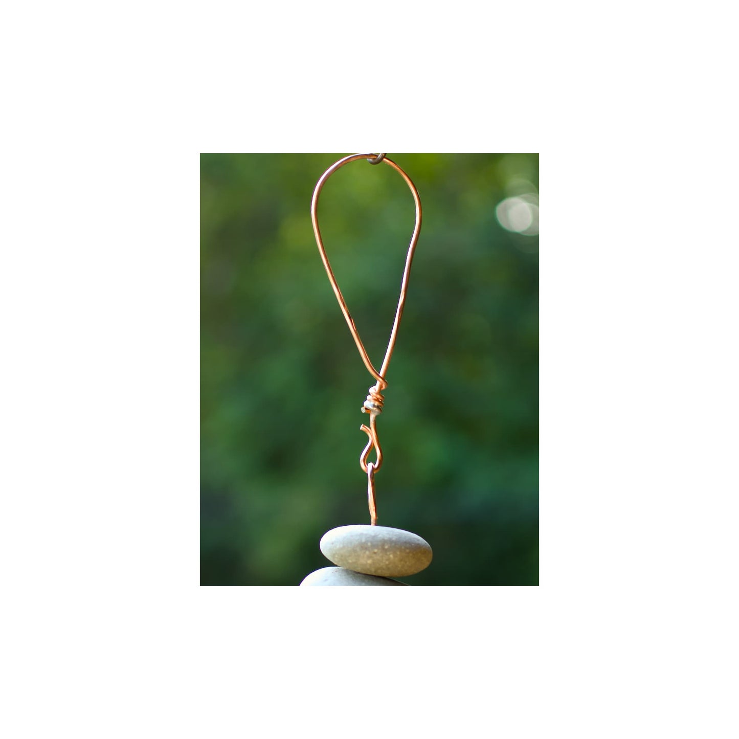 Copper wire hook on a stone with a blurred green background