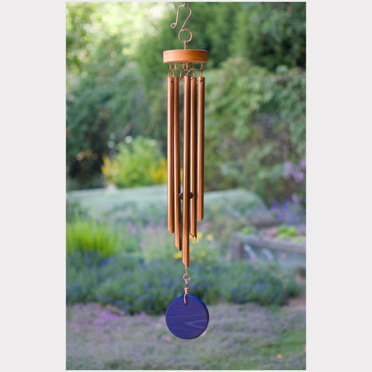 Wind chime with wooden top and blue disc in a garden setting