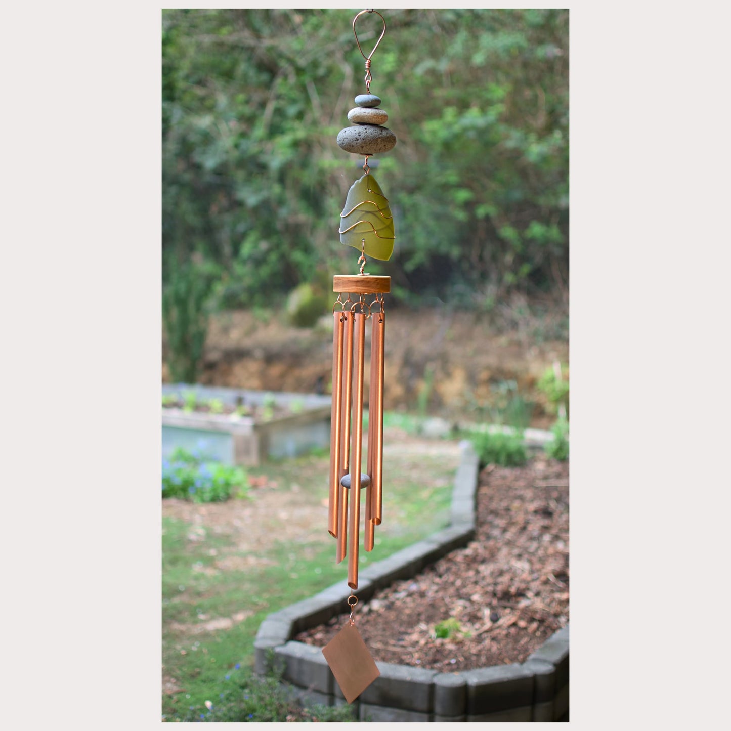 Decorative copper wind chime with beach stones and in garden setting