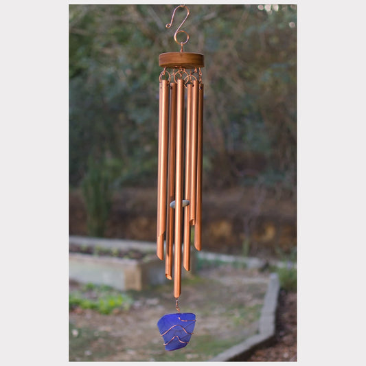 Copper wind chime with  blue glass on a garden background