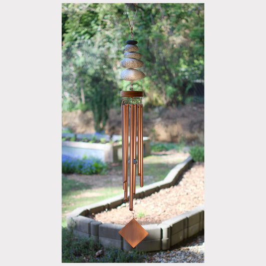 Decorative wind chime with stones on a garden background