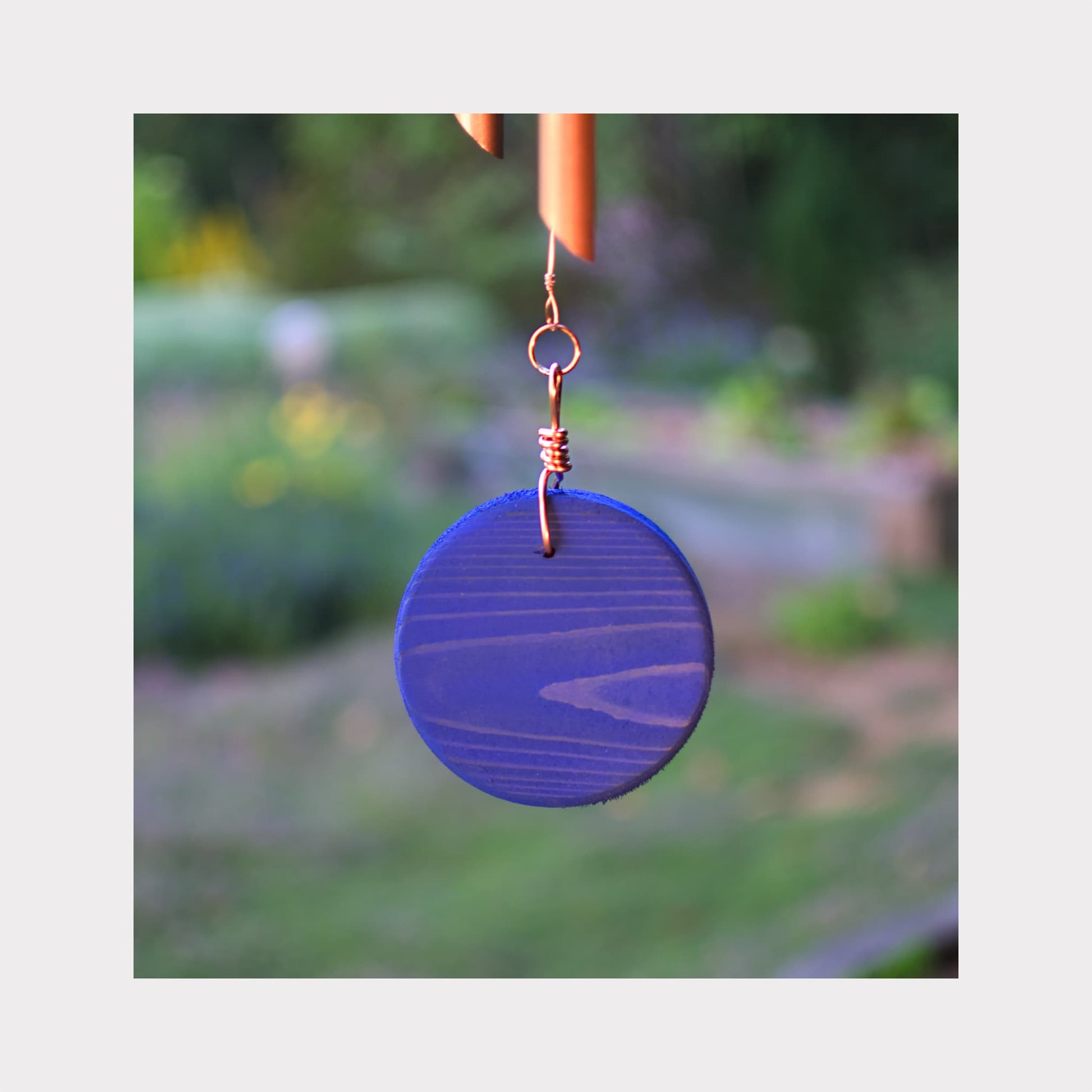 Blue circular windsail with a blurred garden background