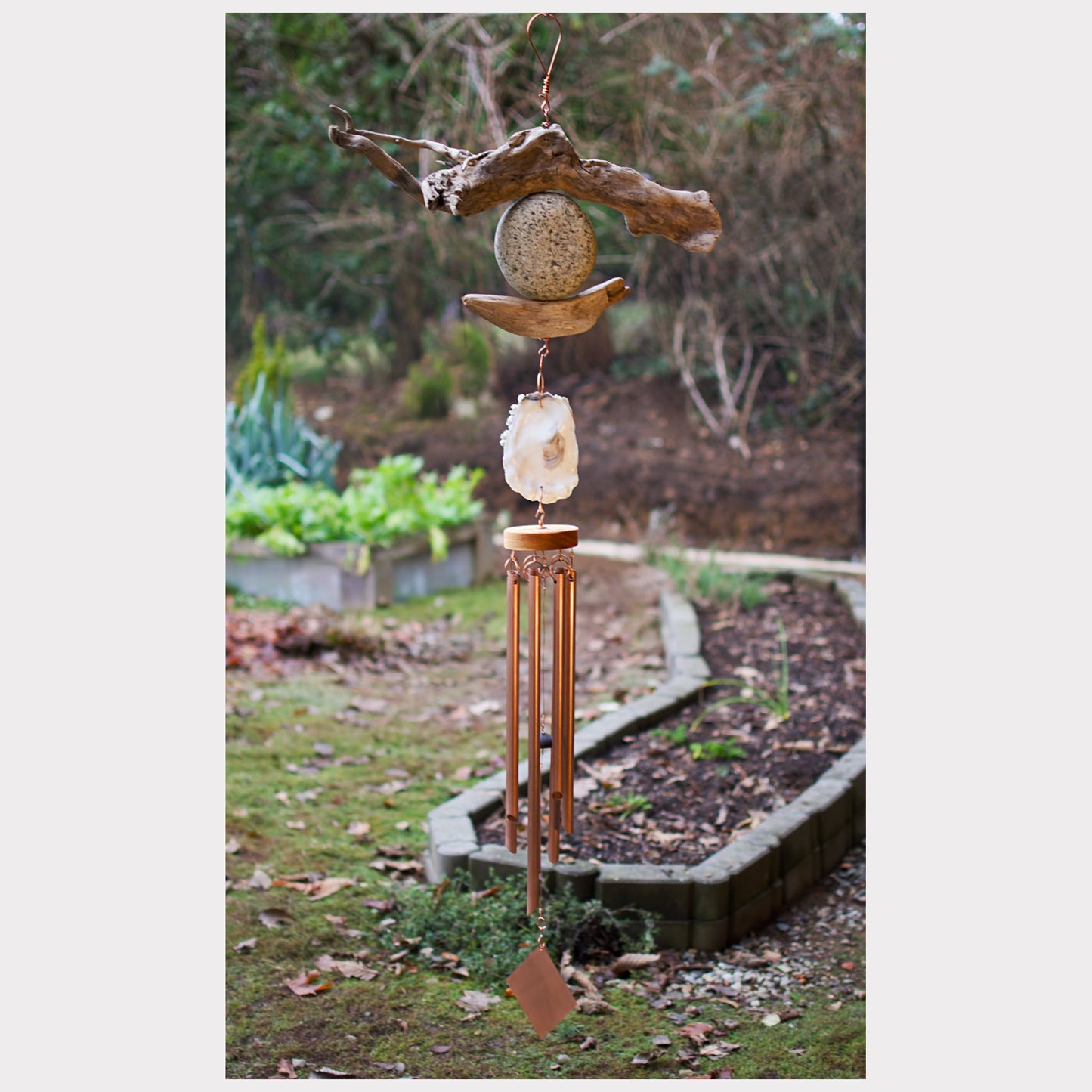 Large driftwood, beach stone, oyster shell wind chime with seven copper chimes.