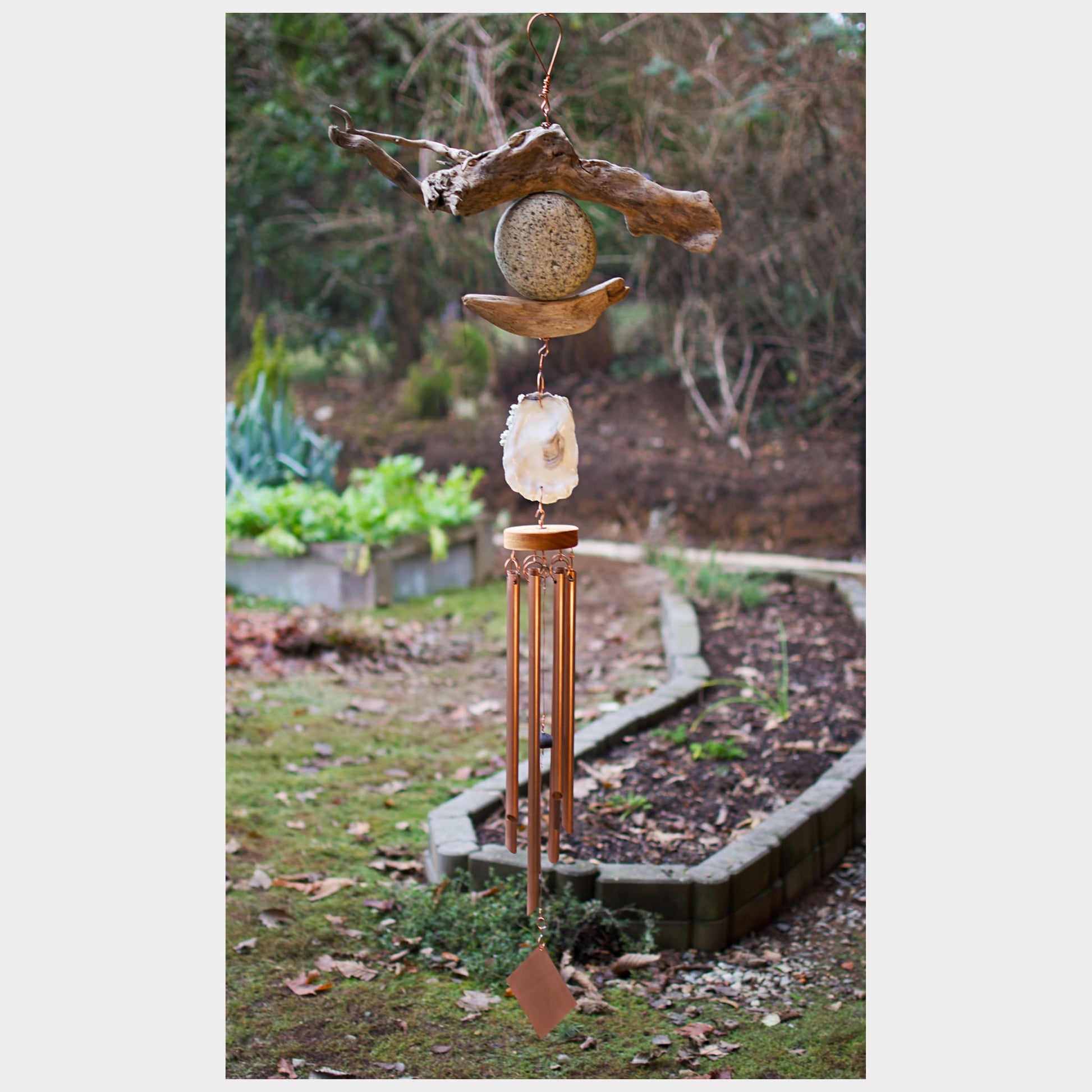 Large driftwood, beach stone, oyster shell wind chime with seven copper chimes.