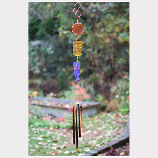 Decorative wind chime with colorful hanging elements against a garden background