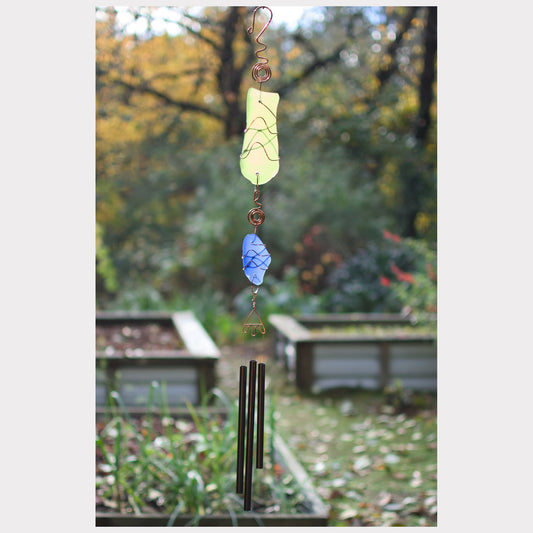 Decorative wind chime with colorful stones against a garden background