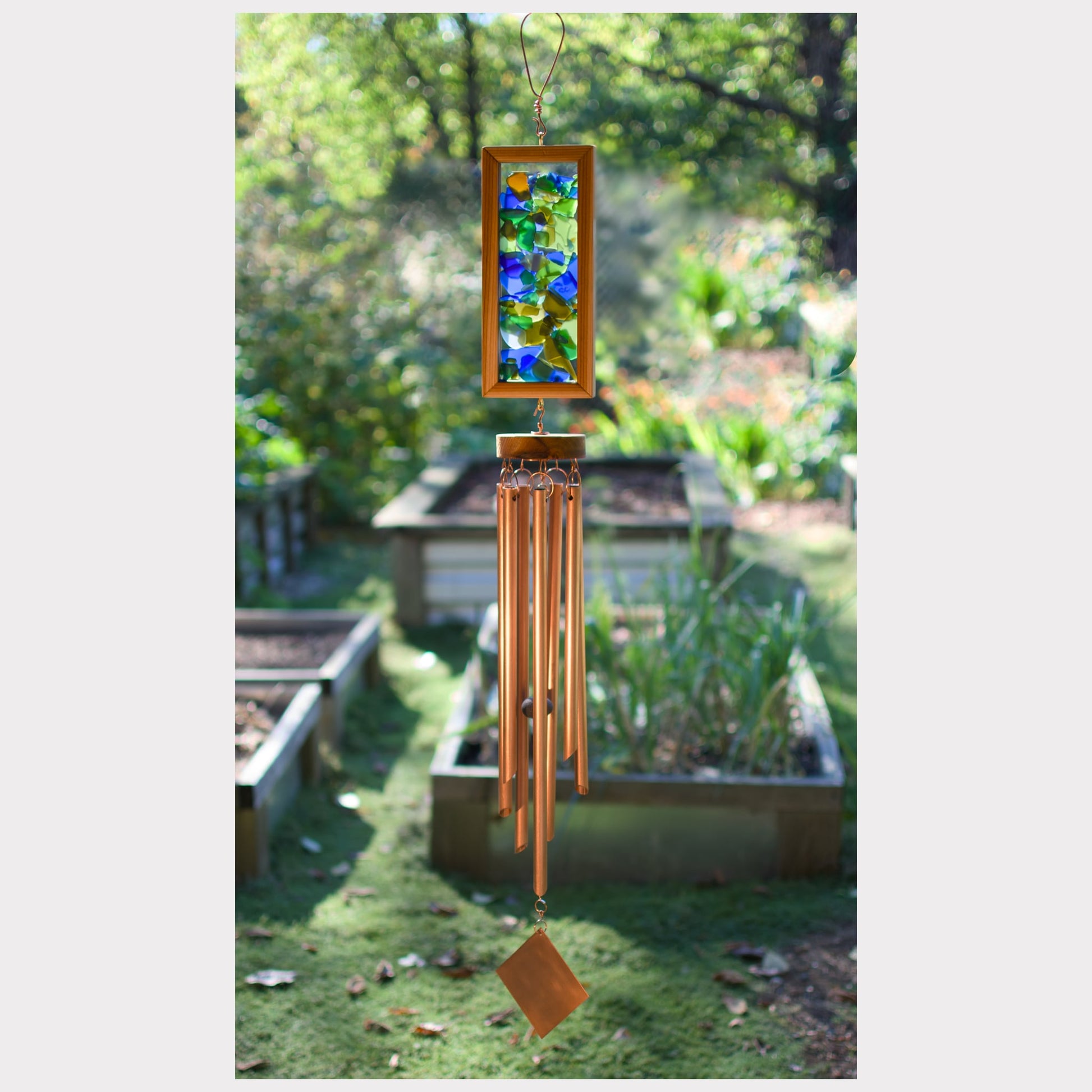 Decorative wind chime with stained glass panel in a garden setting