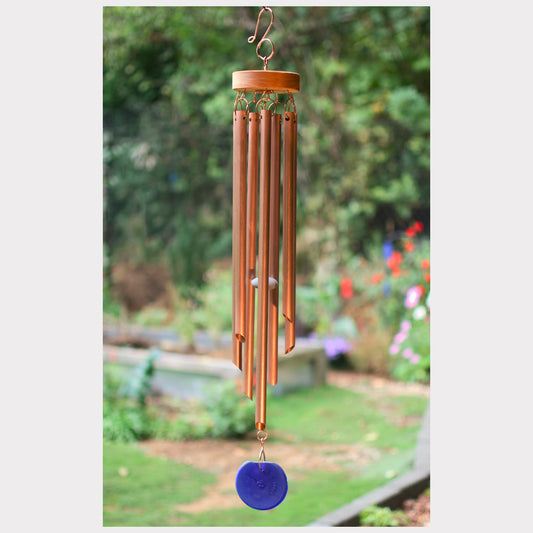 Copper wind chime with a blue disc in a garden setting
