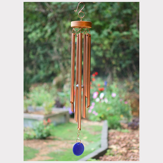 Copper wind chime with a blue disk against a garden background
