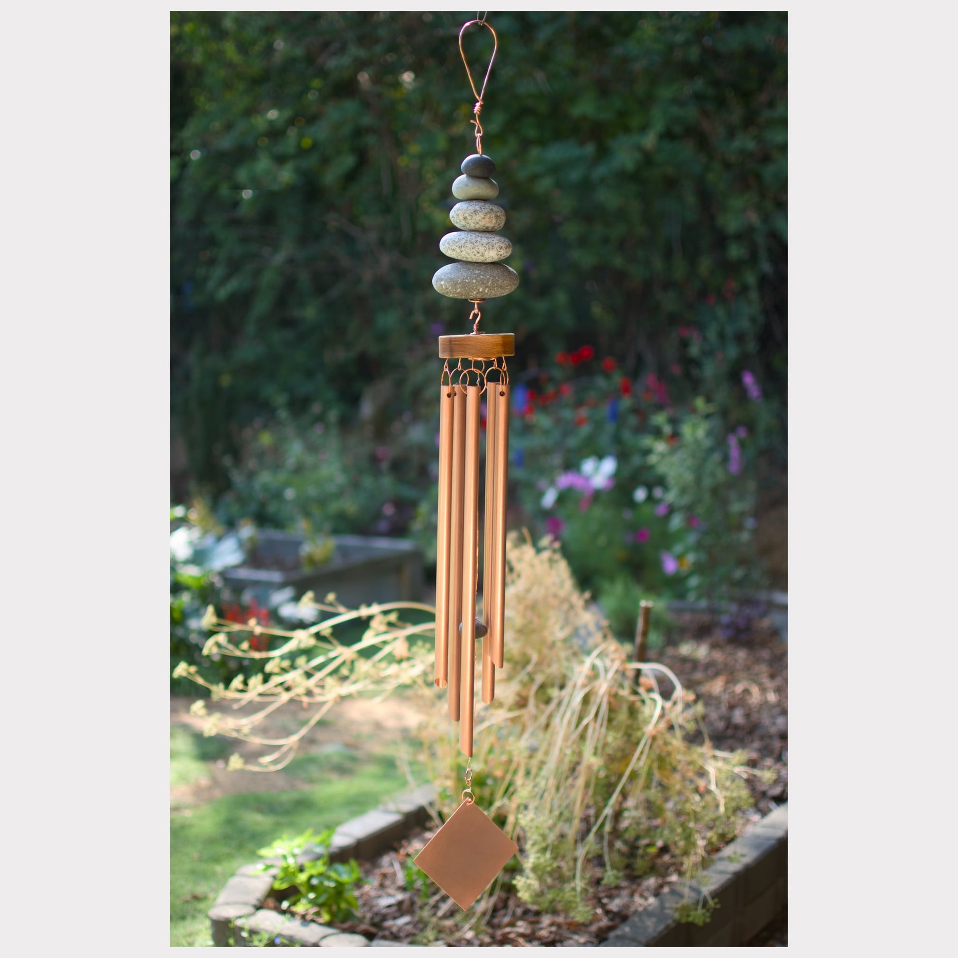 Decorative wind chime with stones hanging in a garden setting