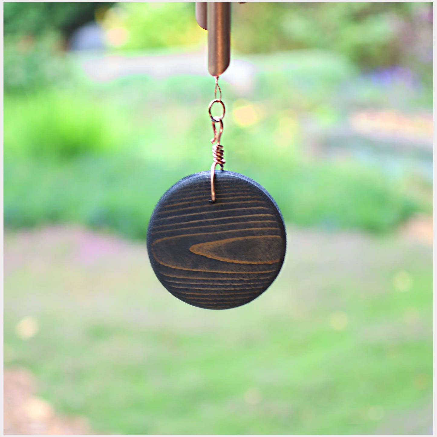 Decorative hanging item with a circular design in a garden setting