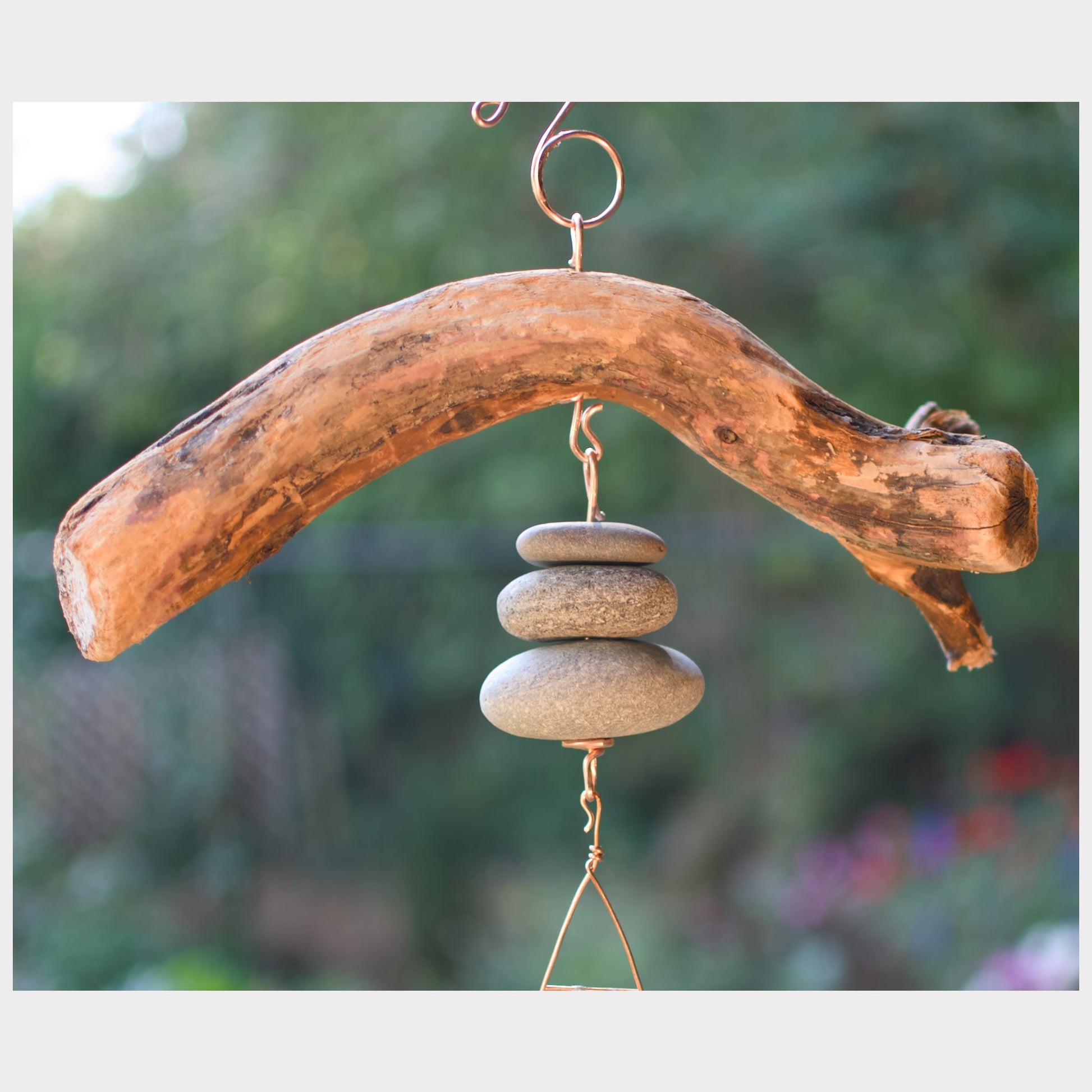 Driftwood and stone wind chime against a blurred natural background