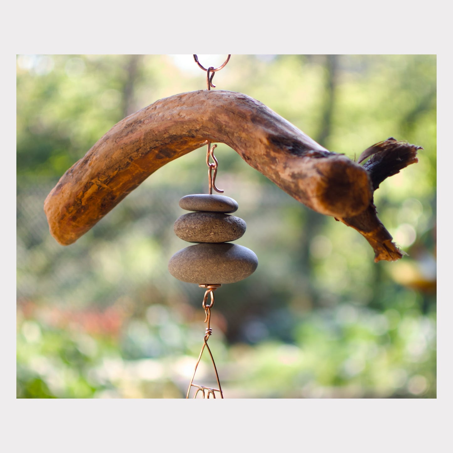 Decorative hanging with driftwood and stones against a blurred natural background