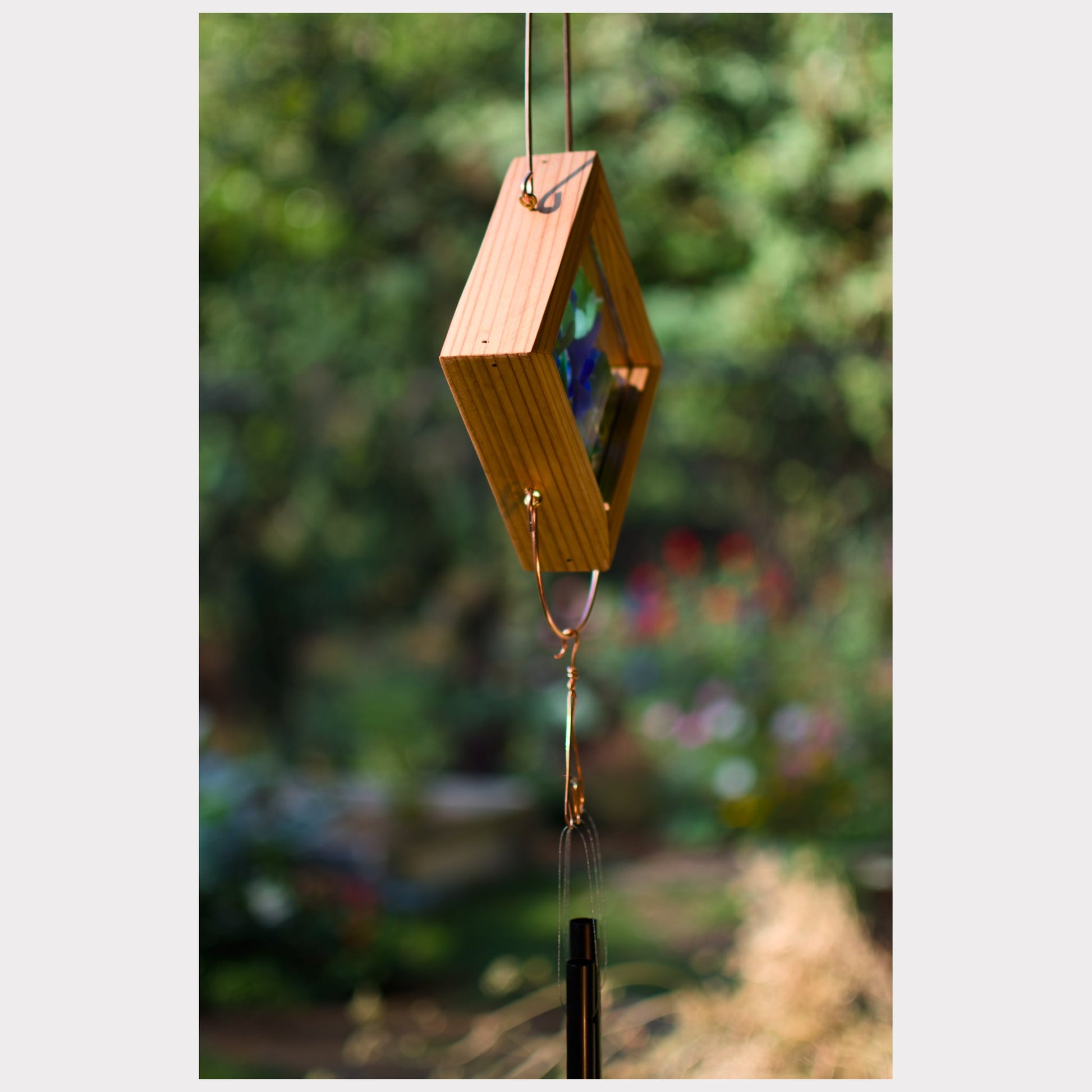 Wooden wind chime with geometric design against a blurred garden background