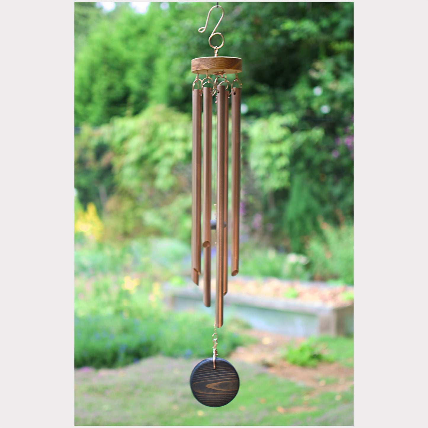 Wind chime hanging outdoors with a garden background