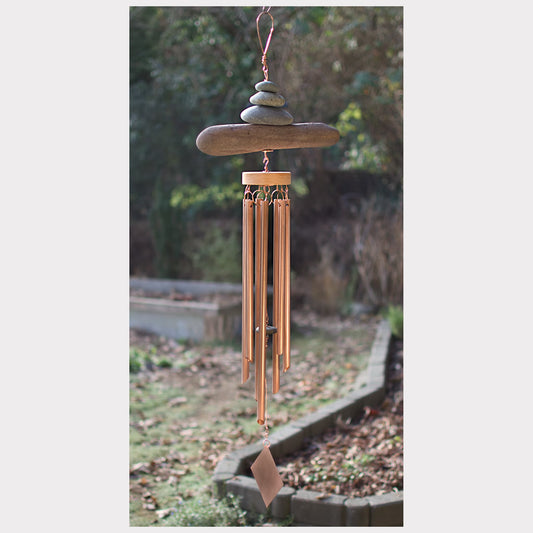 Decorative wind chime with stones on a blurred garden background