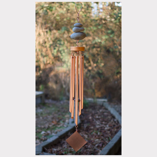 Decorative wind chime with stones on top against a natural background