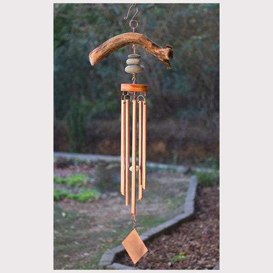 Wooden wind chime with stones and natural elements in a garden setting