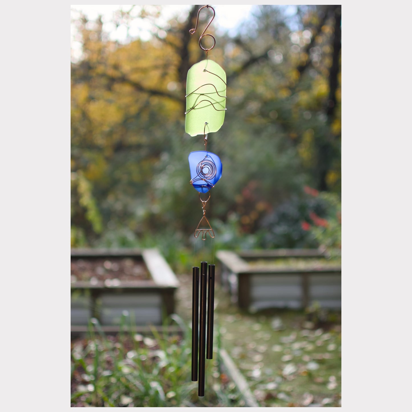 Decorative wind chime with colorful beads against a garden background