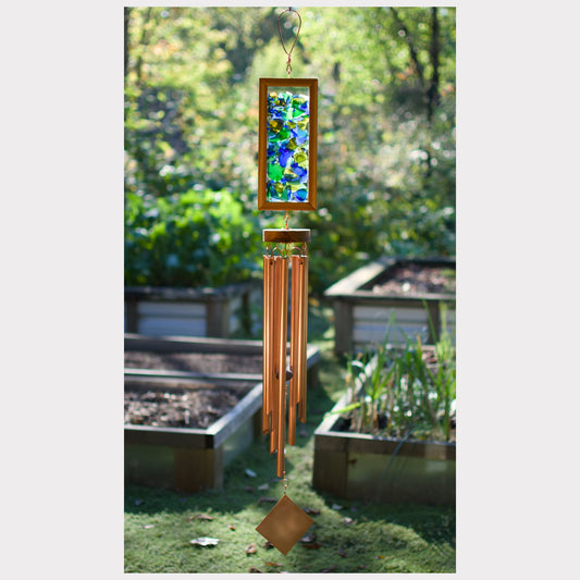 Decorative wind chime with stained glass panel in a garden setting