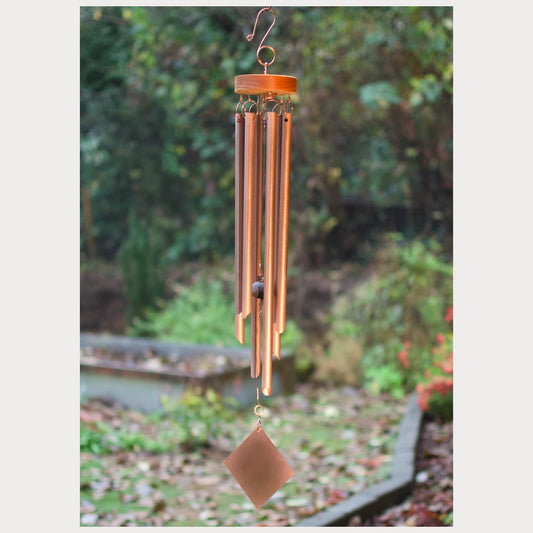 Copper wind chime with a blurred garden background